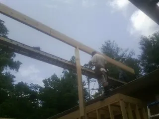 Carpenter setting a ridge beam over a new addition frame — Ice Dam Removal by Roofing Brothers in Walstonburg
