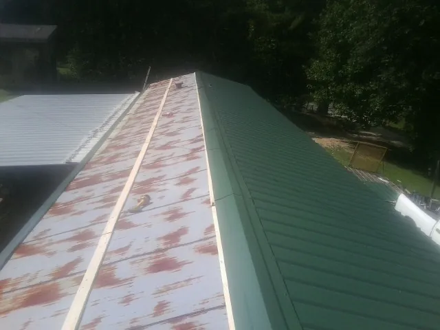 Old rusted panels beside newly installed green metal roofing — Wind Damage Roof Repair by Roofing Brothers in Walstonburg