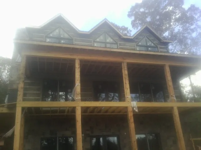 Dormers and porch framing on a large log home under construction — Roof Coating work by our crew in Walstonburg