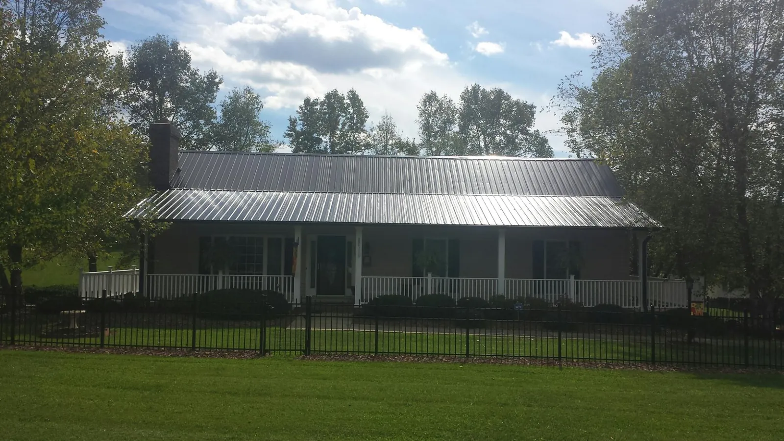Gray metal roof on a brick ranch with a full width front porch — Gutter Guard Installation work by our crew in Walstonburg