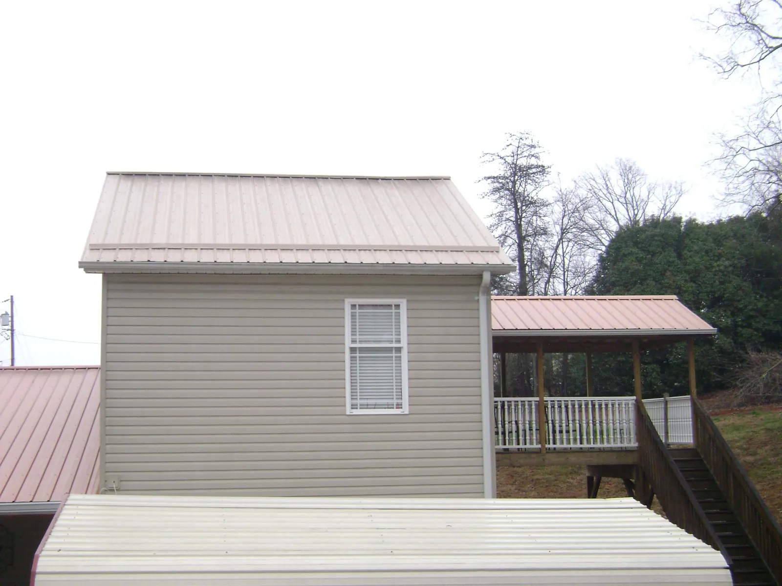 Tan metal roofs on a two story addition and attached porch, from a Roof Replacement job in Walstonburg