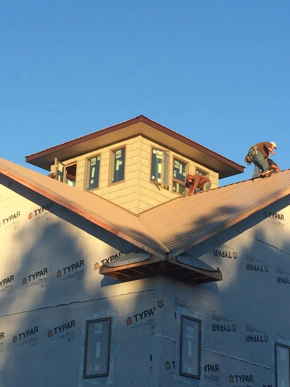 Roofers working around a rooftop cupola on a new metal roof at sunset — Roof Waterproofing in Walstonburg by Roofing Brothers